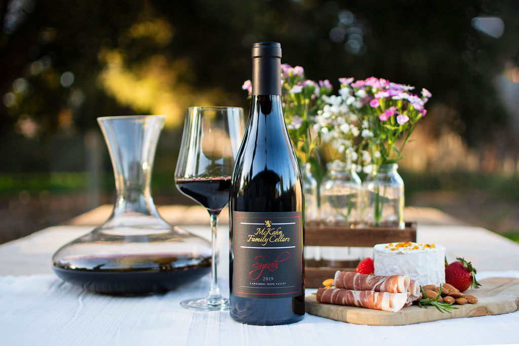 syrah bottle on a table with flowers and charcuterie board