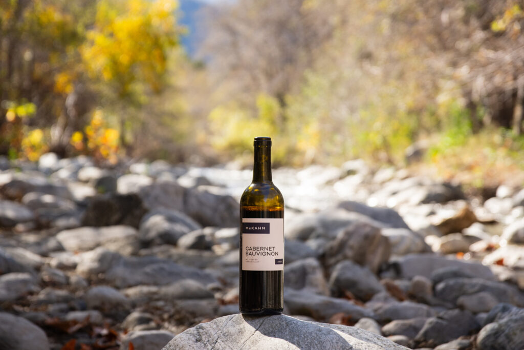 McKahn Cabernet Sauvignon bottle nettled on the rocks in a dry creek.